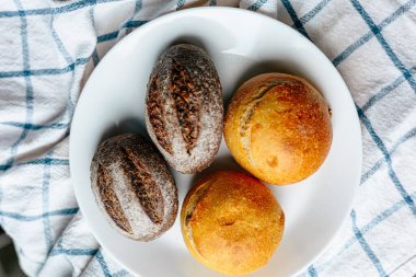 Masanın üzerinde beyaz masa örtüsü olan haşhaş tohumlu çörekler. Asgari stil kavramsal natürmort fotoğrafçılık.