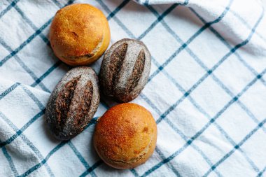 Masanın üzerinde mavi ve beyaz masa örtüsü olan haşhaş tohumlu çörekler. Asgari stil kavramsal natürmort fotoğrafçılık.