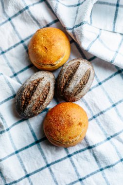 Masanın üzerinde mavi ve beyaz masa örtüsü olan haşhaş tohumlu çörekler. Asgari stil kavramsal natürmort fotoğrafçılık.
