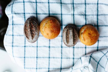 Masanın üzerinde mavi ve beyaz masa örtüsü olan haşhaş tohumlu çörekler. Asgari stil kavramsal natürmort fotoğrafçılık.