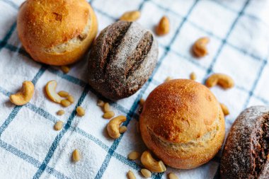 Masanın üzerinde mavi ve beyaz masa örtüsü olan haşhaş tohumlu çörekler. Asgari stil kavramsal natürmort fotoğrafçılık.