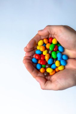 Beyaz arkaplanda renkli m & m şekerleri olan eller