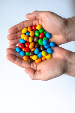 Beyaz arkaplanda renkli m & m şekerleri olan eller