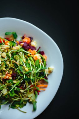 Beyaz tabakta roka ve siyah arka planda taze organik yeşil salata.
