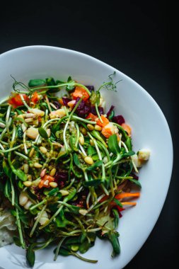 Beyaz tabakta roka ve siyah arka planda taze organik yeşil salata.