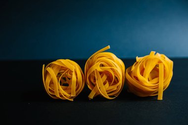 Koyu mavi arka planda İtalyan makarna tagliatelle.