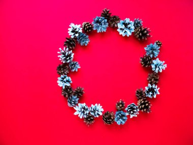 Kırmızı arka planda ren geyiği olan yaratıcı bir Noel çelengi. Yeni yıl afişi. Üst görünüm.