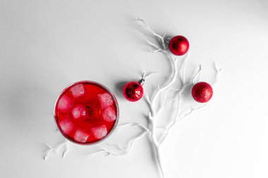 Kırmızı Noel topları beyaz dalda, açık ve koyu arkaplanda. Margarita bardağında köpüklü şarapla birlikte taze kırmızı bir kokteyl. Noel süslemeli Mutlu Noeller kartı. 