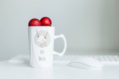 Kırmızı Noel topları beyaz dalda, açık ve koyu arkaplanda. Bir fincanda kırmızı Noel topları. Noel süslemeli Mutlu Noeller kartı. 