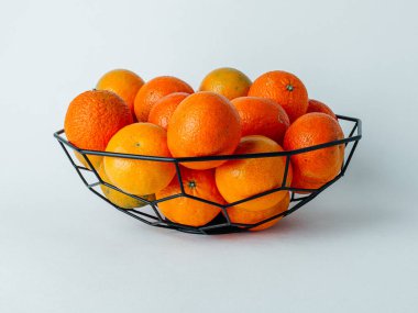 Mandalina ve portakallar demir bir vazoda, yakın plan. Beyaz arka plan. Boşluğu kopyala.