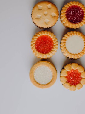 Farklı bisküviler, tatlılar ve kurabiye çerçevesi karışımı. Beyaz ahşap zemin üzerinde fotokopi alanı olan bir masa manzarası. Tatil pişirme konsepti. Kurabiyelerin arka planı çeşitlendirilmiş yakın plan