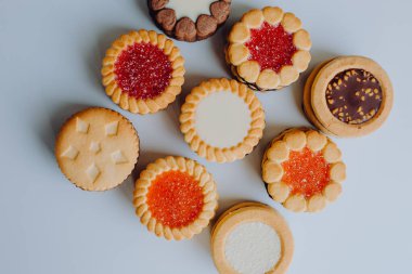 Farklı bisküviler, tatlılar ve kurabiye çerçevesi karışımı. Beyaz ahşap zemin üzerinde fotokopi alanı olan bir masa manzarası. Tatil pişirme konsepti. Kurabiyelerin arka planı çeşitlendirilmiş yakın plan