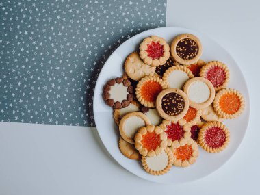 Farklı bisküviler, tatlılar ve kurabiye çerçevesi karışımı. Beyaz ahşap zemin üzerinde fotokopi alanı olan bir masa manzarası. Tatil pişirme konsepti. Kurabiyelerin arka planı çeşitlendirilmiş yakın plan