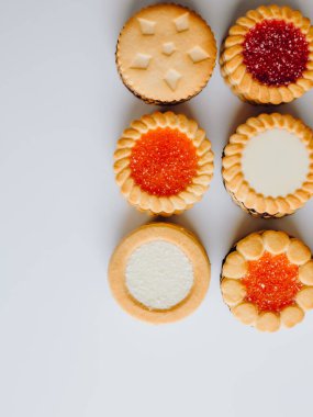 Farklı bisküviler, tatlılar ve kurabiye çerçevesi karışımı. Beyaz ahşap zemin üzerinde fotokopi alanı olan bir masa manzarası. Tatil pişirme konsepti. Kurabiyelerin arka planı çeşitlendirilmiş yakın plan