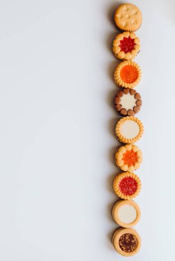 Farklı bisküviler, tatlılar ve kurabiye çerçevesi karışımı. Beyaz ahşap zemin üzerinde fotokopi alanı olan bir masa manzarası. Tatil pişirme konsepti. Kurabiyelerin arka planı çeşitlendirilmiş yakın plan