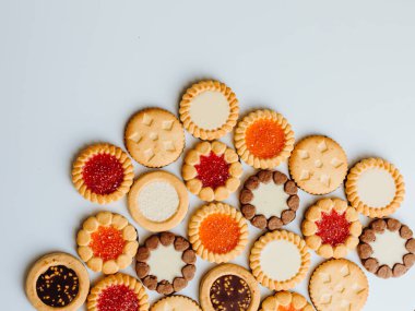 Farklı bisküviler, tatlılar ve kurabiye çerçevesi karışımı. Beyaz ahşap zemin üzerinde fotokopi alanı olan bir masa manzarası. Tatil pişirme konsepti. Kurabiyelerin arka planı çeşitlendirilmiş yakın plan