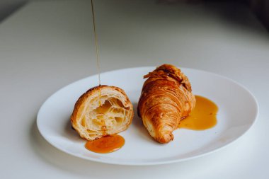 Akçaağaç şuruplu iki taze kruvasan beyaz arka planda izole edilmiş.