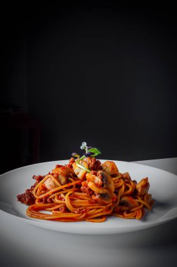 Domates soslu İtalyan Lezzetli makarna, parmesan ve şampiyon mantarı. Bolonez koyu arkaplanda beyaz bir tabakta servis edilir.. 