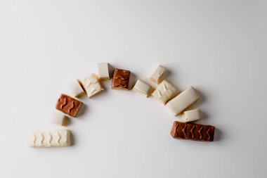 Çikolata piramidi. Beyaz ve koyu arkaplan üzerine izole edilmiş, fındıklı çikolataya (karamel kaplı, sütlü çikolatayla kaplı) yakın plan. Çikolata parçaları..