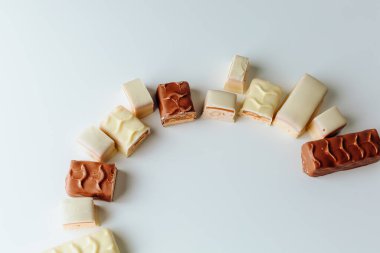 Çikolata piramidi. Beyaz ve koyu arkaplan üzerine izole edilmiş, fındıklı çikolataya (karamel kaplı, sütlü çikolatayla kaplı) yakın plan. Çikolata parçaları..