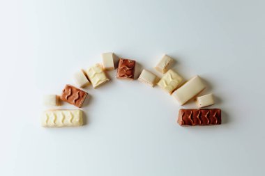 Çikolata piramidi. Beyaz ve koyu arkaplan üzerine izole edilmiş, fındıklı çikolataya (karamel kaplı, sütlü çikolatayla kaplı) yakın plan. Çikolata parçaları..