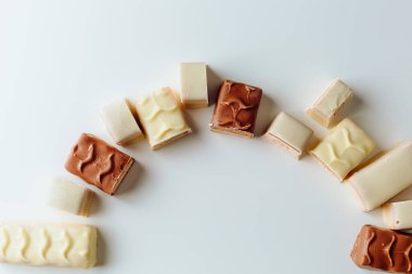 Çikolata piramidi. Beyaz ve koyu arkaplan üzerine izole edilmiş, fındıklı çikolataya (karamel kaplı, sütlü çikolatayla kaplı) yakın plan. Çikolata parçaları..