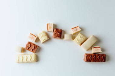 Çikolata piramidi. Beyaz ve koyu arkaplan üzerine izole edilmiş, fındıklı çikolataya (karamel kaplı, sütlü çikolatayla kaplı) yakın plan. Çikolata parçaları..