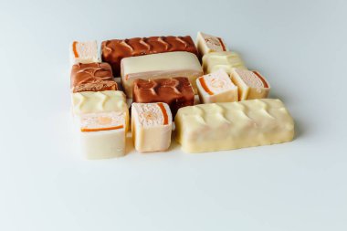 Çikolata piramidi. Beyaz ve koyu arkaplan üzerine izole edilmiş, fındıklı çikolataya (karamel kaplı, sütlü çikolatayla kaplı) yakın plan. Çikolata parçaları..