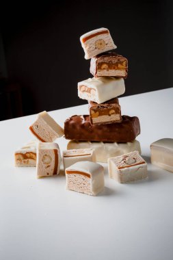 Çikolata piramidi. Beyaz ve koyu arkaplan üzerine izole edilmiş, fındıklı çikolataya (karamel kaplı, sütlü çikolatayla kaplı) yakın plan. Çikolata parçaları..