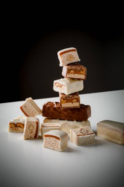 Çikolata piramidi. Beyaz ve koyu arkaplan üzerine izole edilmiş, fındıklı çikolataya (karamel kaplı, sütlü çikolatayla kaplı) yakın plan. Çikolata parçaları..