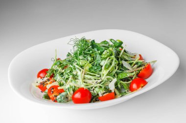 Mikroyeşil turp filizli taze salata, kiraz domatesleri, beyaz tabakta siyah susam, beyaz arka plan. Vejetaryen ve sağlıklı beslenmeyi düşün..