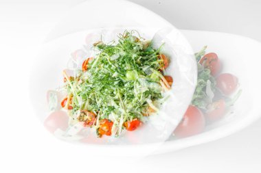 Mikroyeşil turp filizli taze salata, kiraz domatesleri, beyaz tabakta siyah susam, beyaz arka plan. Vejetaryen ve sağlıklı beslenmeyi düşün..