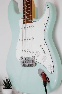 Beyaz bir duvarda yeşil elektro gitar sörfü.