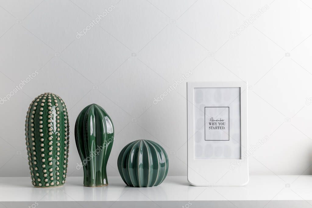 Decorative artificial ceramic cactus, succulent and cactuses on white wall background. Candlesticks and candles.