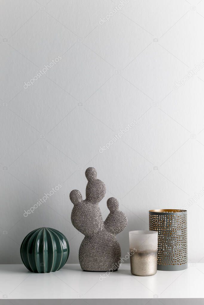 Decorative artificial ceramic cactus, succulent and cactuses on white wall background. Candlesticks and candles.