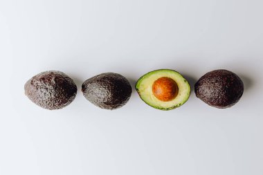 Yeşil ve beyaz arka planda taze organik avokadolar. Kırpma yolu ile. Taze, yarım ve dilimlenmiş avokado izole, üst görünüm..