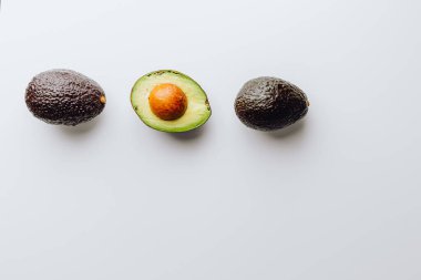 Yeşil ve beyaz arka planda taze organik avokadolar. Kırpma yolu ile. Taze, yarım ve dilimlenmiş avokado izole, üst görünüm..