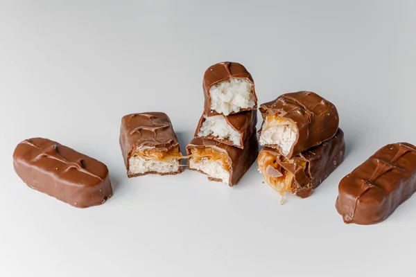 Delicious chocolate bars with nuts close up. Chocolate candy bar Bounty. Snickers bar isolated on white background. Pieces of chocolate bars.