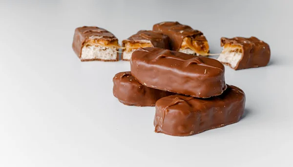 Delicious chocolate bars with nuts close up. Chocolate candy bar Bounty. Snickers bar isolated on white background. Pieces of chocolate bars.