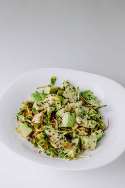 Beton arka planda avokado ve sos ile taze karışık salata. Buzdağından organik sağlıklı salata, avokado ve zeytinyağı ve susam tohumlu salatalık. Sağlıklı yeşil salata.. 