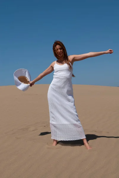 長いブロンドの髪の女性が白い服を着た砂丘を歩く — ストック写真