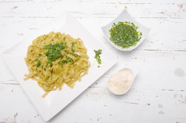 Bir tabak rendelenmiş peynirli erişte ve pesto