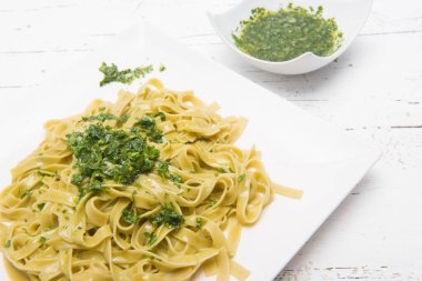 Bir tabak rendelenmiş peynirli erişte ve pesto