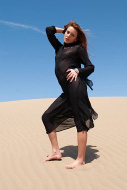 Çölde siyah cüppeli Müslüman bir kadın.