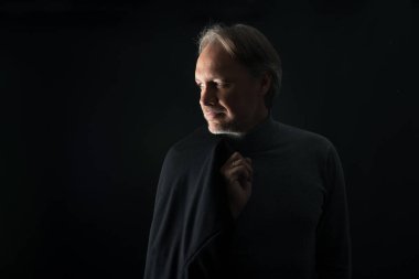 Sıradan giyinen, sakallı, olgun, çekici bir adam.