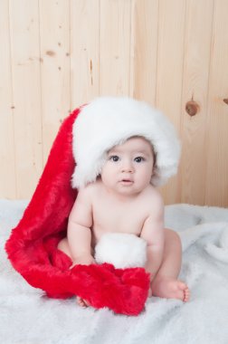 bir Noel Baba takım elbise ve şapka bir ahırda Noel giyen genç bebek