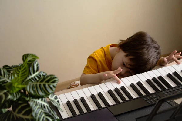 Мальчик устал играть на синтезаторе — стоковое фото