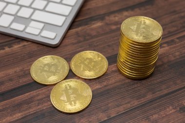 Sanal para birimi Altın Bitcoin beyaz klavye ve ahşap zemin üzerine uzanır.