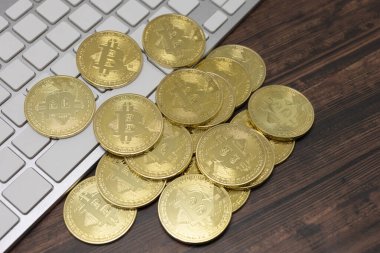 Tokyo, Japonya, 20 Ocak 2021 - Sanal para birimi Altın Bitcoin beyaz bir klavye ve ahşap zemin üzerine uzanmış.
