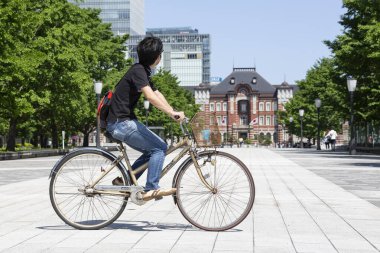 Tokyo, Japonya, 18 Mayıs 2020 - Bisikletli bir adam Tokyo İstasyonu 'ndan geçiyor.